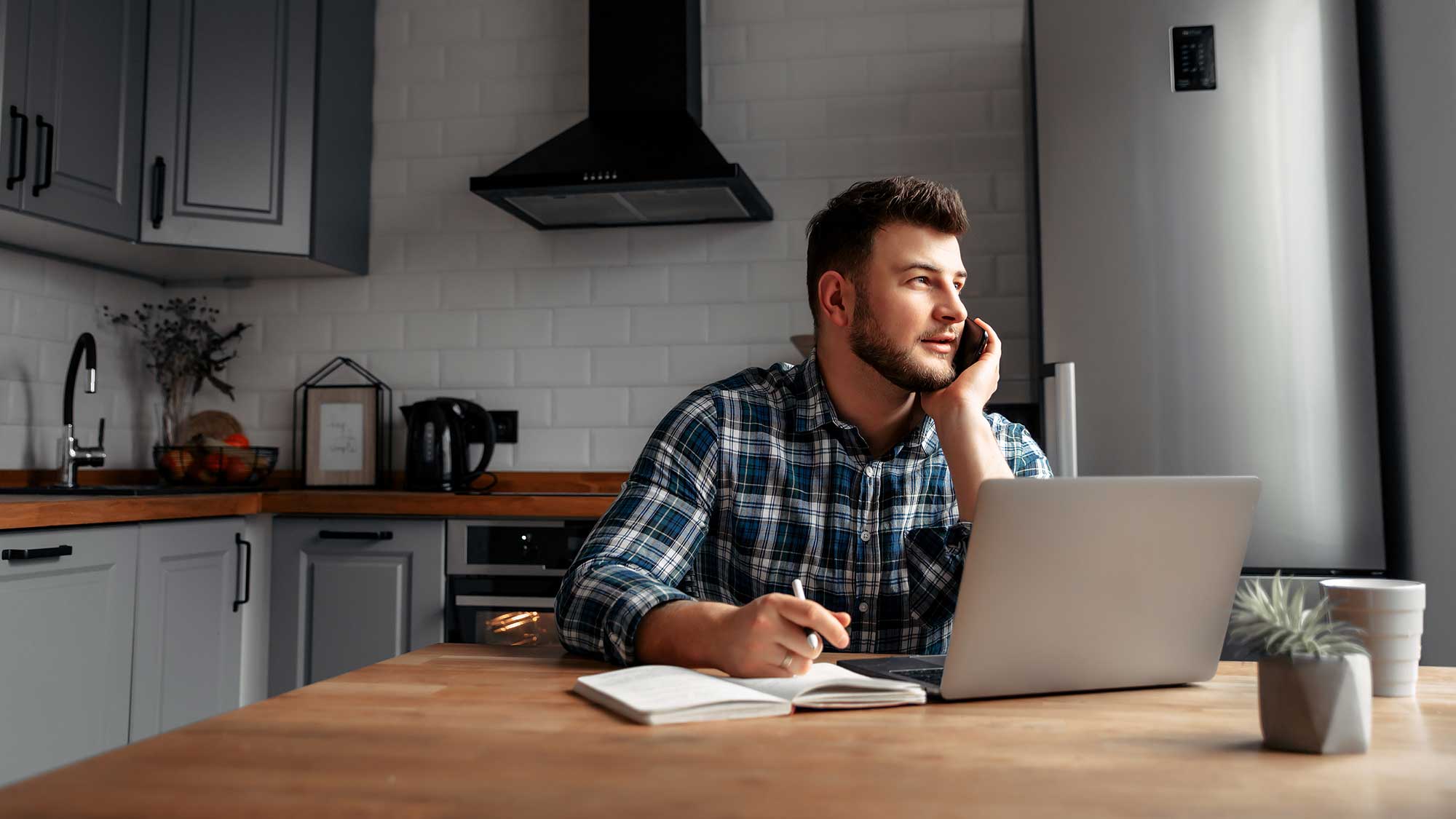man working from home on the phone taking notes